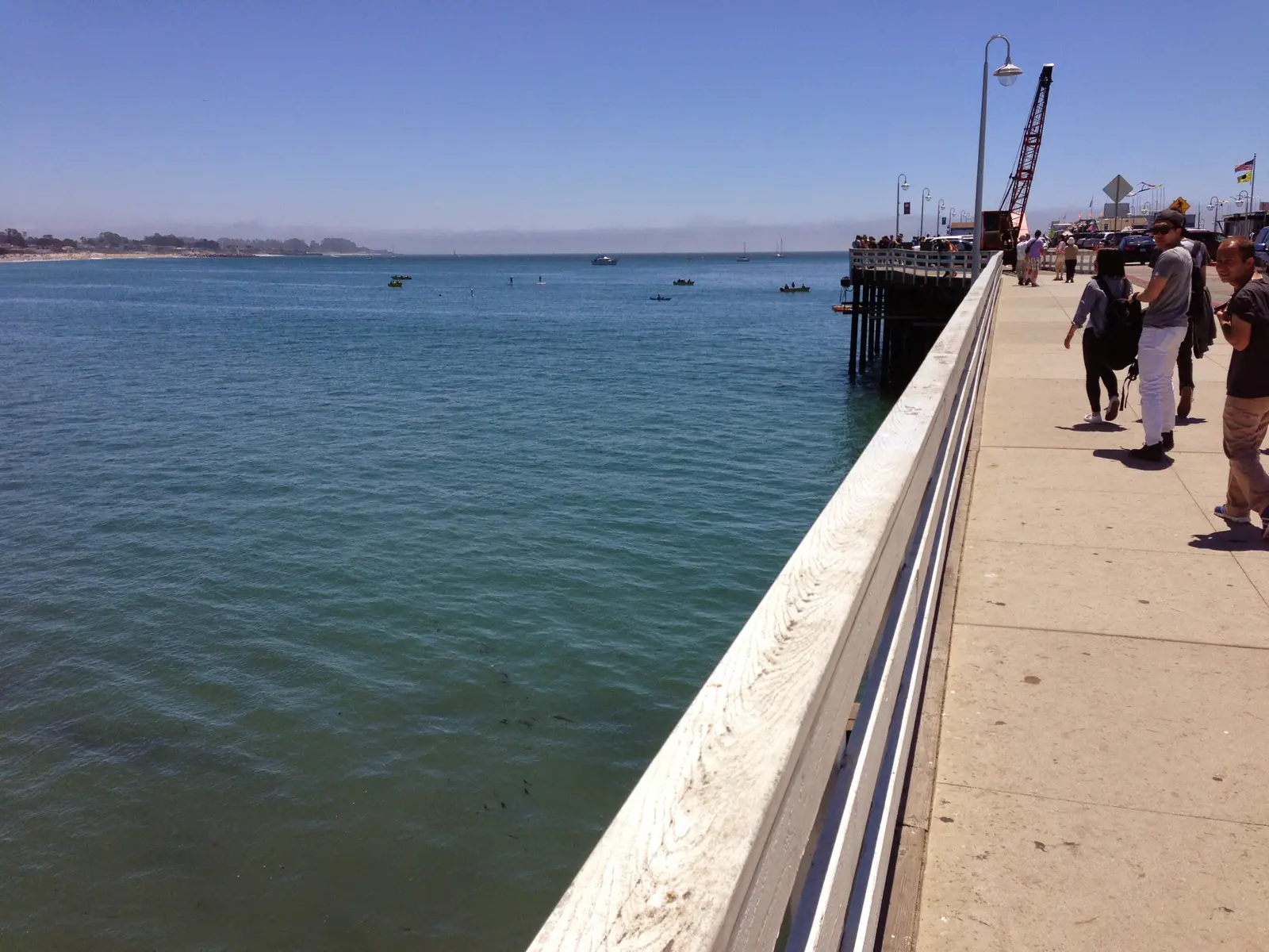 Pedestrians walking along the Santa Cruz Municipal Wharf with Monterey Bay beside them.